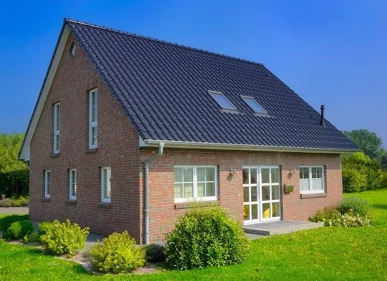 Freistehendes Haus mit Satteldach, die Fassade besteht aus rotbraunen Backsteinen.
