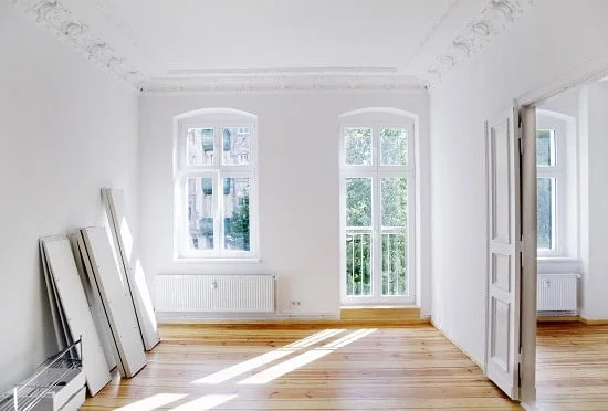Ansicht eines Raumes mit zwei Fenster in Barock-Stil mit Holzboden und offener Türe.